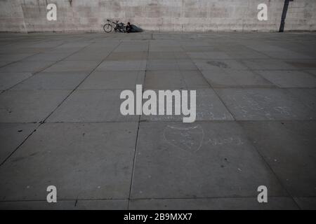 Londres, Royaume-Uni. 24 mars 2020. Un homme se trouve au soleil à l'extérieur de la Galerie nationale de Trafalgar Square le premier jour d'un verrouillage national. Crédit: Oliver Weiken/dpa/Alay Live News Banque D'Images