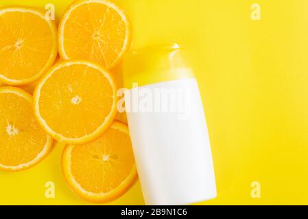 Crème solaire sur fond jaune avec des tranches d'orange. Maquette de marque de produit de beauté cosmétique pour hydrater la crème, la lotion, le sérum ou l'huile essentielle. Vue de dessus. Banque D'Images