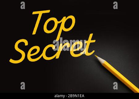 Mots top secret écrits avec un stylo jaune sur fond noir. Concept d'entreprise Banque D'Images