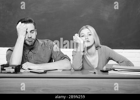 Problèmes de vie des étudiants. S'ennuyer. Étudier au collège ou à l'université. Demandez un programme gratuit. Couple amis étudiant université. Guy et la fille fatiguée ou étudiant paresseux se penchent sur le bureau dans la salle de classe. Banque D'Images