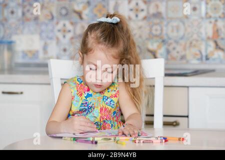 Créativité pour les enfants. Petite fille puise avec des crayons de cire à la maison. Le concept d'apprentissage à distance en ligne pour la période de quarantaine mondiale. Banque D'Images