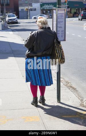 La femme attend un bus de ville sur une rue vide pendant le temps du Coronavirus à Brooklyn, New York. Banque D'Images