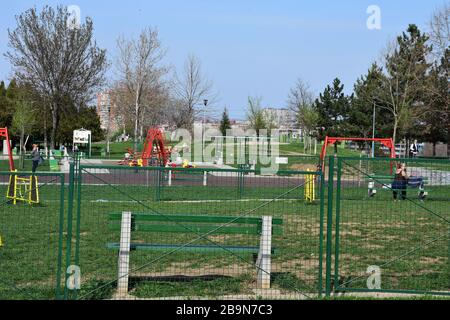 Clôture en métal vert. Il y a un banc vert derrière la clôture. Il y a des appareils pour enfants dans le parc Banque D'Images