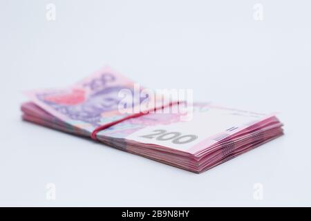 Beaucoup de nouveaux billets en coupures de 200 hryvnias ukrainiens bandés avec une bande élastique isolée sur un fond blanc avec ombre. Européen m Banque D'Images