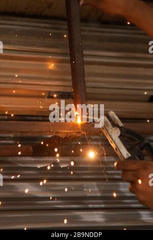 Le travailleur soudure une partie métallique des détails de la trappe de levage de roulement du système. Mise au point sélective. Banque D'Images