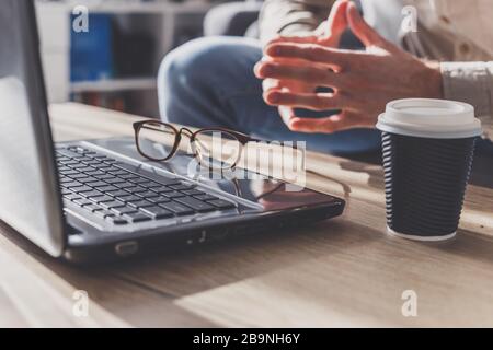 L'homme fatigué après de longues années de travail ou s'énerve, se replia les mains. Tasse à café sur la table près de l'ordinateur portable. Banque D'Images