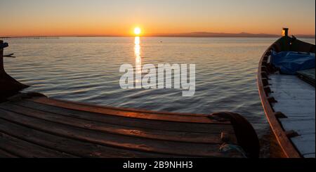 Vue panoramique au rez-de-chaussée d'une jetée en bois avec un bateau en bois avec le soleil à l'horizon dans le lagon côtier de Valence, Espagne. Ntu Banque D'Images