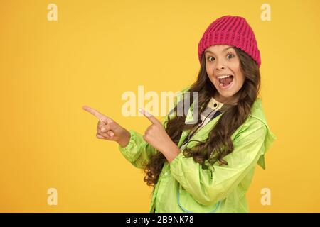 Choisissez entre plus mignonne et la plus branchée. Des cheveux longs de fille fond jaune. Saison froide concept. Accessoire de mode d'hiver. Petit enfant portant chapeau chaud. Kid girl porter chapeau tricoté. Bonnet hiver accessoire. Banque D'Images