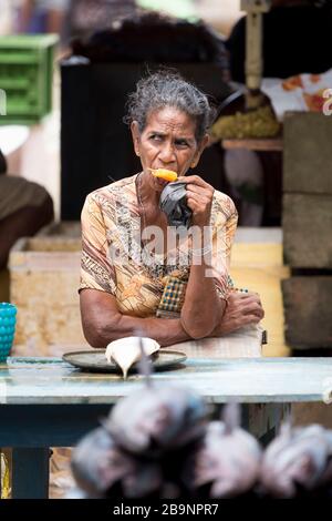 Femme se rafraîchissant avec un bloc de glace au marché du poisson de Negombo, Sri Lanka Banque D'Images