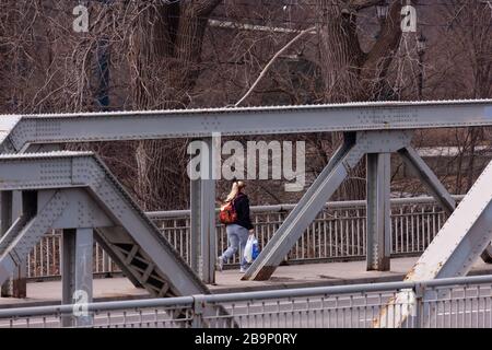 Une femme qui tient un sac d'épicerie traverse un pont à London, au Canada, au cours de la pandémie COVID-19. Banque D'Images