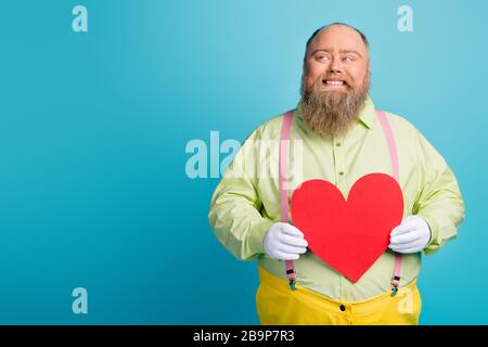 Portrait de son sympathique drôle heureux rêveuse gaie gai homme tenant dans les mains grand coeur créant la première date de stratégie d'idée isolée sur lumineux Banque D'Images