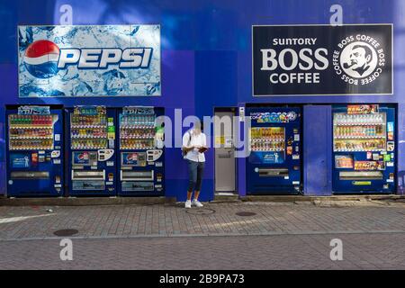 Un homme vérifie son portefeuille par quelques distributeurs automatiques au Centre Gai, Shibuya, Tokyo, Japon Banque D'Images