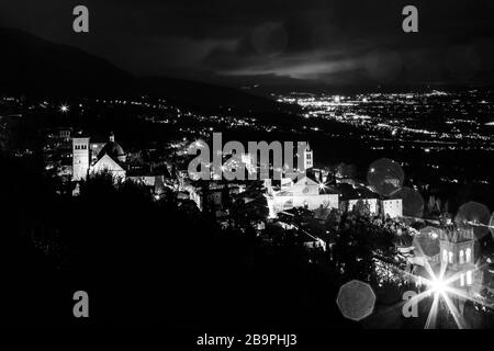Vue aérienne de la ville d'Assise (Ombrie, Italie) et de la vallée la nuit, avec lumières de la ville et église Santa Chiara Banque D'Images