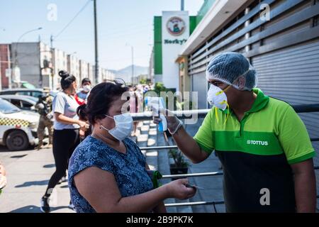 Un employé de supermarché contrôle la température corporelle d'un client.en raison de la menace de la pandémie de coronavirus, le 15 mars, le président Vizcarra a déclaré l'état d'urgence national et la suspension de l'exercice des droits constitutionnels liés à la liberté et à la sécurité personnelles, inviolabilité du domicile et liberté de réunion et de transit sur le territoire pendant 15 jours. Actuellement, au Pérou, il y a 416 cas enregistrés et 7 décès de Covid-19. Banque D'Images