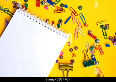 Fournitures de bureau de boutons de couleur et de trombones avec bloc-notes vide avec espace de copie sur fond jaune Banque D'Images