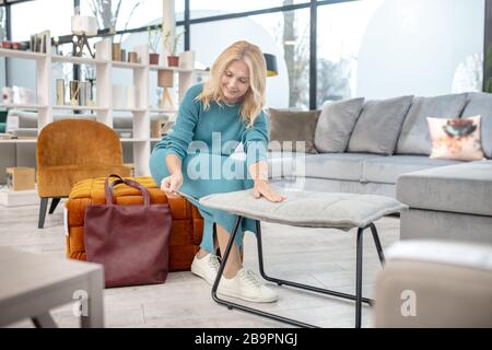 Femme assise sur un fauteuil bas en regardant une étiquette. Banque D'Images