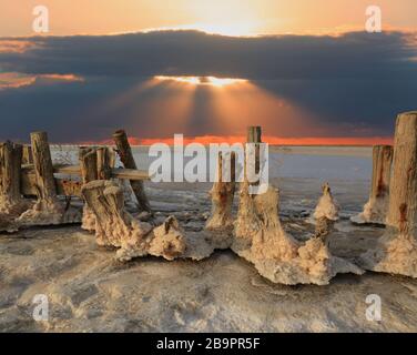 Beau paysage vieux poteaux en bois dans un lac de sel sur fond de coucher de soleil du ciel rouge Banque D'Images