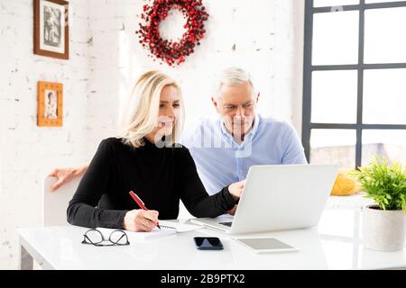Couple mûr faisant des finances de famille à la maison. Couple senior discutant de l'économie de la maison tout en étant assis au bureau et en utilisant un ordinateur portable. Banque D'Images