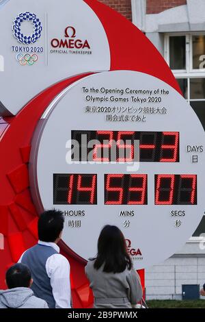 Tokyo, Japon. 25 mars 2020. Les piétons regardent une horloge Omega, qui a été utilisée comme horloge de compte à rebours des Jeux olympiques et paralympiques de Tokyo 2020, et qui montre actuellement l'heure et la date, à l'extérieur de la gare de Tokyo. Le compte à rebours a cessé d'afficher le nombre de jours avant la cérémonie d'ouverture de Tokyo 2020 après le Comité International Olympique (CIO) et le gouvernement japonais a décidé de reporter les Jeux jusqu'en 2021 en réponse à la pandémie mondiale de coronavirus. Crédit: Rodrigo Reyes Marin/ZUMA Wire/Alay Live News Banque D'Images