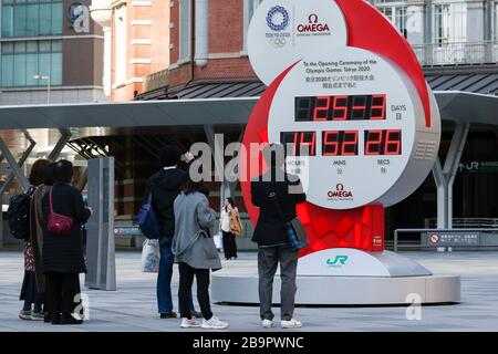 Tokyo, Japon. 25 mars 2020. Les piétons prennent des photos d'une horloge Omega, utilisée comme horloge de compte à rebours des Jeux olympiques et paralympiques de Tokyo 2020, et montrant actuellement l'heure et la date, à l'extérieur de la gare de Tokyo. Le compte à rebours a cessé d'afficher le nombre de jours avant la cérémonie d'ouverture de Tokyo 2020 après le Comité International Olympique (CIO) et le gouvernement japonais a décidé de reporter les Jeux jusqu'en 2021 en réponse à la pandémie mondiale de coronavirus. Crédit: Rodrigo Reyes Marin/ZUMA Wire/Alay Live News Banque D'Images