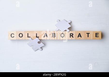 Mot à la mode moderne pour les entreprises - collaborer. Puzzle avec vue sur le dessus, blocs de bois. Gros plan. Vue de dessus. Banque D'Images