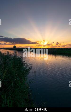 Belle image de paysage des rayons de soleil sur un lac au coucher du soleil Banque D'Images