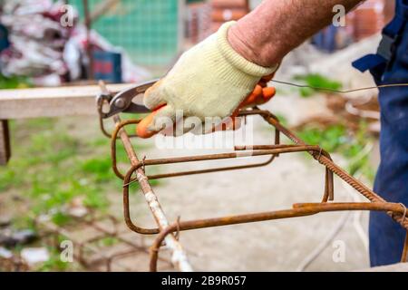 Travailleur est de lier avec du fil d'armature à l'aide de pinces, de faire un châssis poutre en béton pour renforcer. Banque D'Images