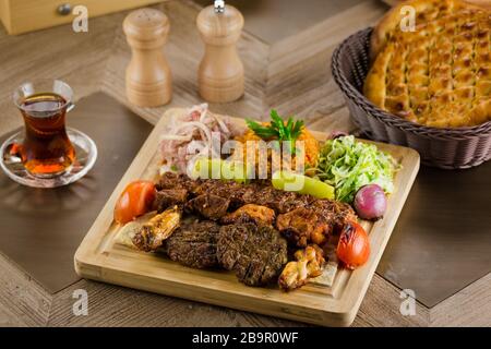La vue du mélange Persique Kebab de viandes hachées et de poulet avec du riz et des frites et des légumes dans un grand bac en bois traditionnel sur table Banque D'Images