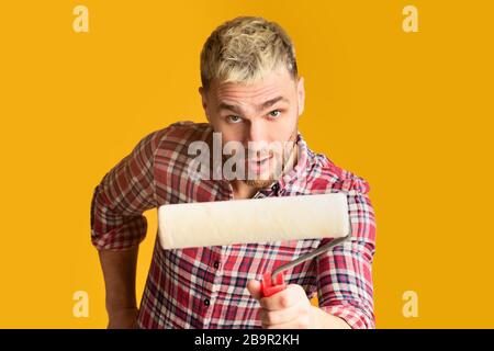 Homme drôle dans une chemise avec rouleau de peinture Banque D'Images