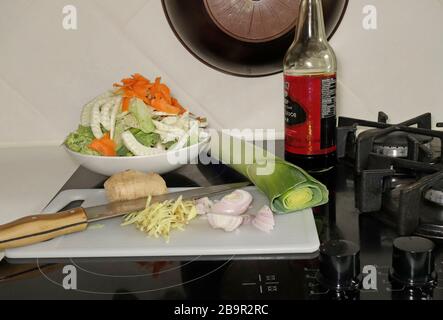 Couper, râper des légumes crus sur un poêle dans un pantry préparé pour un simple wok plat. Banque D'Images