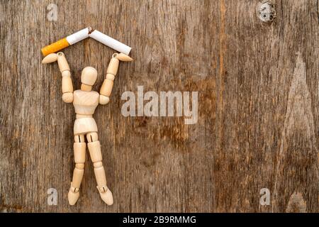 Cesser de fumer - homme en bois écrasant la cigarette. Concept d'arrêt du tabagisme. Banque D'Images