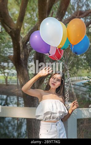 Portrait de la jolie femme asiatique avec des ballons dans le jardin vert Banque D'Images