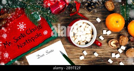 Concept de lettre au Père Noël. Papier sur fond en bois avec décoration Cristomas et tasse de chocolat chaud, vue de dessus. Banque D'Images