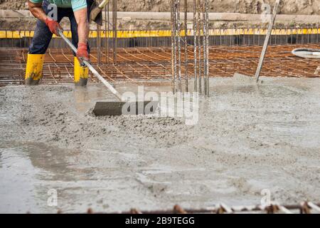 bricklayer au travail sur un site de construction pendant la pose de béton pour construire les fondations d'une maison Banque D'Images