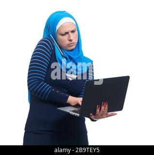 Femme arabe qui parle sur téléphone mobile et utilise un ordinateur portable. Concept multitâche Banque D'Images