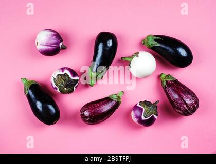 Aubergines fraîches de différentes couleur et variété sur un fond rose, vue du dessus Banque D'Images