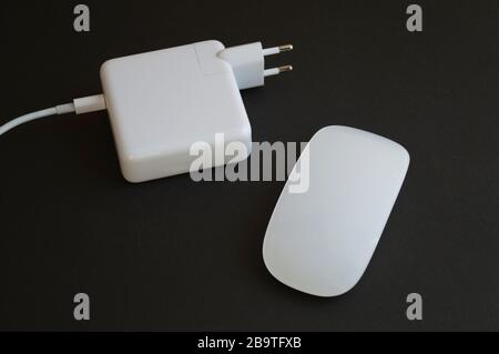 Combinaison minimaliste de souris blanche et chargeur pour ordinateur portable sur fond sombre Banque D'Images