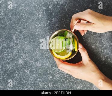 Woman's hands holding une tasse de cuivre de limonade à la menthe fraîche, vue du dessus, copy space Banque D'Images
