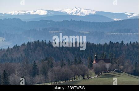 25 mars 2020, Bade-Wuerttemberg, Saint-Märgen: L'Ohmenkapelle se dresse devant le Feldberg enneigé au soleil. Photo : Patrick Seeger/dpa Banque D'Images