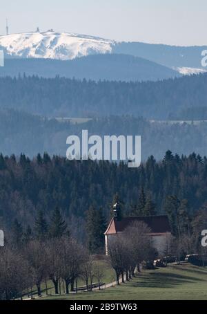 25 mars 2020, Bade-Wuerttemberg, Saint-Märgen: L'Ohmenkapelle se dresse devant le Feldberg enneigé au soleil. Photo : Patrick Seeger/dpa Banque D'Images