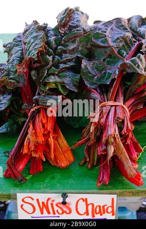 Bouquets de la bette à carde rouge vif et orange avec les tiges et feuilles vertes à la vente à un marché de producteurs Banque D'Images