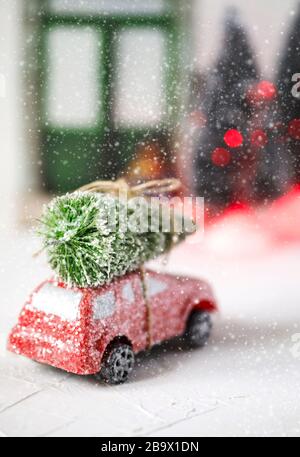 Voiture rouge rétro jouet livrant arbre de Noël. Carte de vacances Banque D'Images