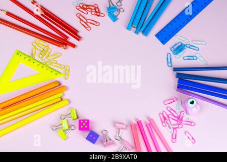 Les règles, les stylos, les crayons, les ciseaux et les articles de papeterie aux crayons multicolores sont sur un fond rose Banque D'Images