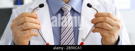 Les mains du médecin de médecine masculine tiennent et mettent sur stéthoscope Banque D'Images