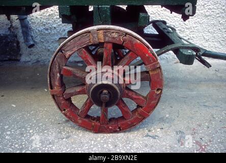 Une roue de chariot en bois peinte à la main et peinte en rouge avec un pneu en fer sur une remorque rustique à Paxos, Grèce Banque D'Images