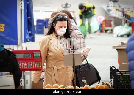 Les gens, avec des masques pour la protection de COVID-19, font du shopping de légumes et de fruits sur le marché. Turin, Italie - Mars 2020 Banque D'Images