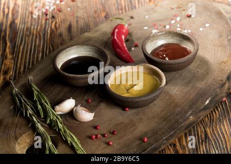 Ingrédients, ail, romarin, piment, sauce tomate et soja, moutarde, épices, poivre rouge et noir, sel sur un magnifique fond en bois sombre, Banque D'Images