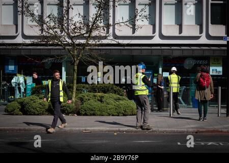 Manchester, Royaume-Uni. 25 mars 2020. Les travailleurs de la construction pratiquent la distanciation sociale à l'extérieur d'un supermarché à l'heure du déjeuner. Le Cabinet Office a confirmé que la construction en Angleterre peut se poursuivre tant qu'elle peut être effectuée en toute sécurité et en suivant les directives de Santé publique Angleterre. La sécurité des travailleurs de la construction a été largement controversée en raison de la propagation du coronavirus. Crédit : Andy Barton/Alay Live News Banque D'Images