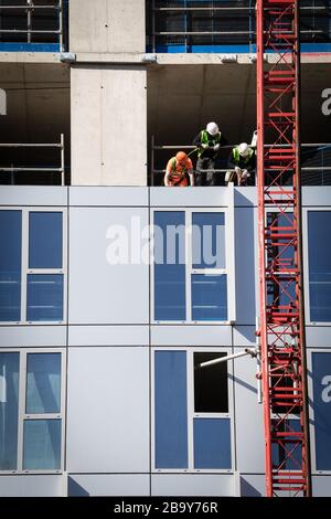 Manchester, Royaume-Uni. 25 mars 2020. Les travailleurs de la construction installent des travaux de revêtement à proximité les uns des autres. Le Cabinet Office a confirmé que la construction en Angleterre peut se poursuivre tant qu'elle peut être effectuée en toute sécurité et en suivant les directives de Santé publique Angleterre. La sécurité des travailleurs de la construction a été largement controversée en raison de la propagation du coronavirus. Crédit : Andy Barton/Alay Live News Banque D'Images