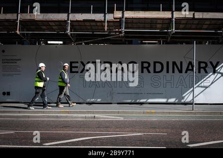 Manchester, Royaume-Uni. 25 mars 2020. Les travailleurs de la construction quittent le chantier lors de leur pause déjeuner.le Cabinet Office a confirmé que la construction en Angleterre peut se poursuivre tant qu'elle peut être effectuée en toute sécurité et conformément aux directives de Santé publique Angleterre. La sécurité des travailleurs de la construction a été largement controversée en raison de la propagation du coronavirus. Crédit : Andy Barton/Alay Live News Banque D'Images